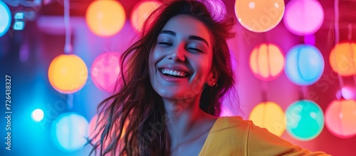 Happy young woman dancing at disco party with neon light background in a portrait.