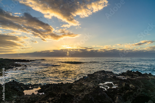 sunset with water refelction over the sea from the coast of the pacific on big island in hawaii