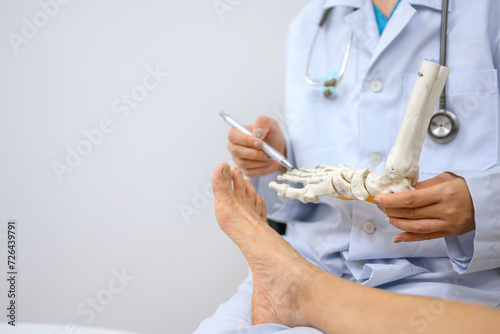 Wallpaper Mural An orthopedic doctor holding a model of ankle and foot bones is explaining to a patient foot bone problems. Concept of health care for feet and foot bones Torontodigital.ca