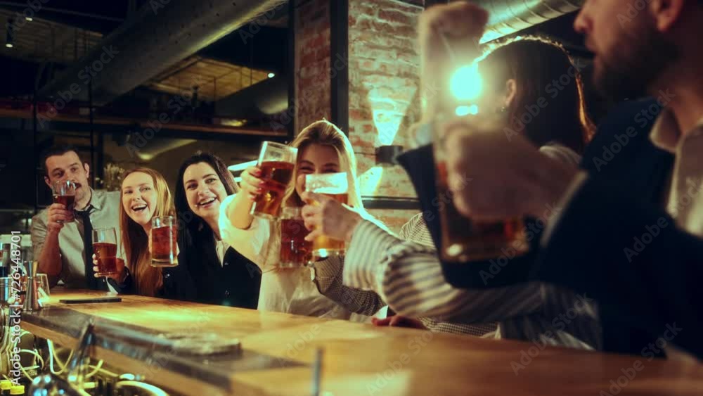 Cheers. Friends, colleagues sitting at pub, clinking glasses drinking foamy lager beer, talking, laughing,. Good time and relaxation. Concept of leisure time, friendship, fun and joy, youth, enjoyment Cheers. Friends, colleagues sitting at pub, clinking glasses drinking foamy lager beer, talking, laughing,. Good time and relaxation. Concept of leisure time, friendship, fun and joy, youth, enjoyment