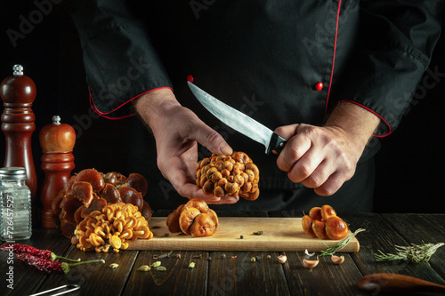 A professional chef prepares fresh mushrooms in a restaurant kitchen. Cleaning flammulina mushrooms before sorting and cooking photo