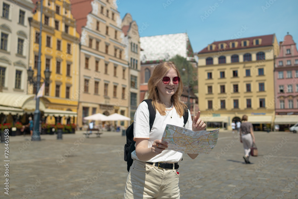 Woman with city map and smart phone. Fantastic view of the ancient homes on a sunny day. Gorgeous and picturesque scene. Location famous Market Square in Wroclaw, Poland, Europe. Historical capital of