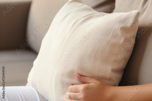 Pregnant woman with pillow on sofa at home, closeup © Creative