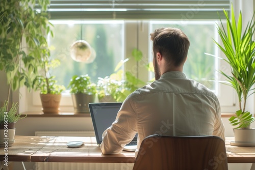 Man in a shirt sitting at the desk with laptop at home, freelancer working from home
