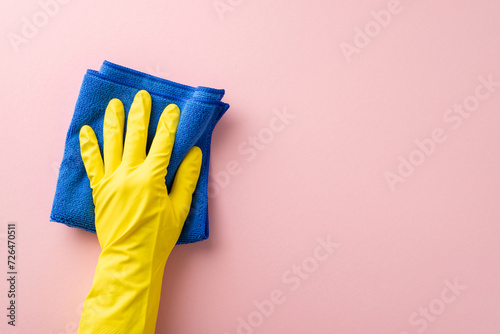Ideal for housekeeping tasks, this image showcases a hand in a rubber glove, effortlessly wiping with a microfiber cloth on a soft pink surface, leaving ample space for text or advertising photo