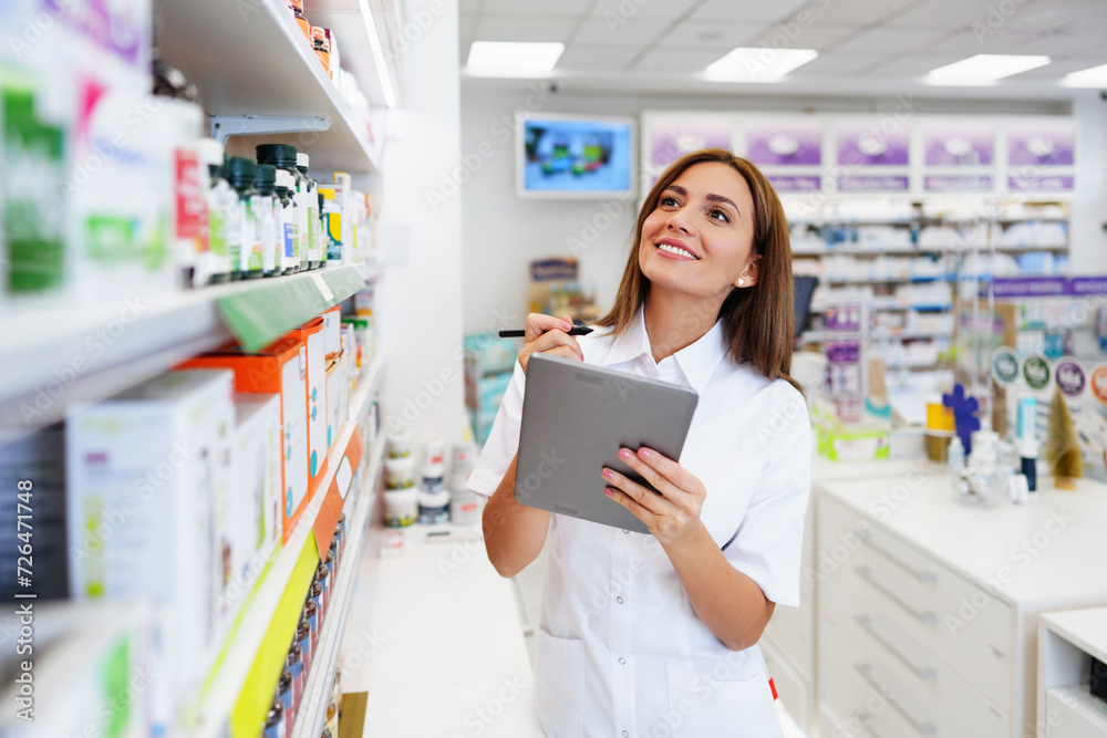 Beautiful pharmacist working and standing in a drug store and doing a stock take. Portrait of a positive healthcare worker or a chemist at his work.