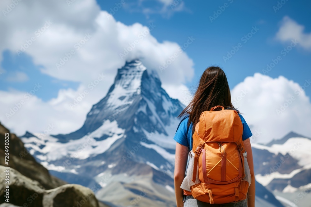 woman with backpack looking at mountain peak