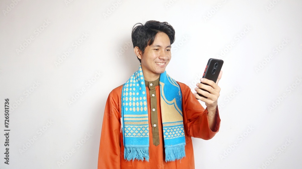 Excited Asian Muslim man is holding a smartphone Excited Asian Muslim man is holding a smartphone