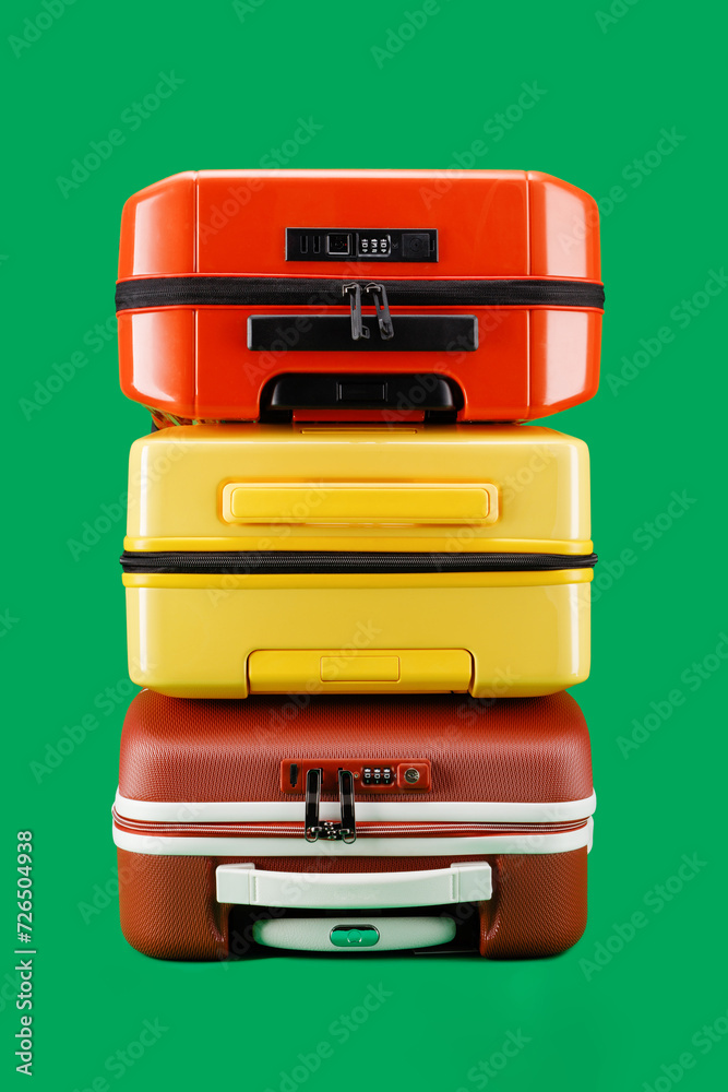 Stack of suitcases on a green background. Travel yellow, orange color, brown suitcase on a green background. Travel and vacation concept in triples. Trolley suits Stack of suitcases on a green background. Travel yellow, orange color, brown suitcase on a green background. Travel and vacation concept in triples. Trolley suits