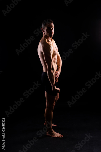 Handsome bodybuldier man posing showing muscle, shirtless torso showing pectorals and sixpack