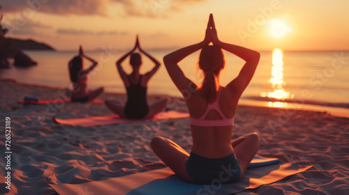 Against the backdrop of the setting sun, a group of young women performs yoga exercises, merging with the coastal beauty of the ocean. Their practice is filled with tranquility and well-being photo