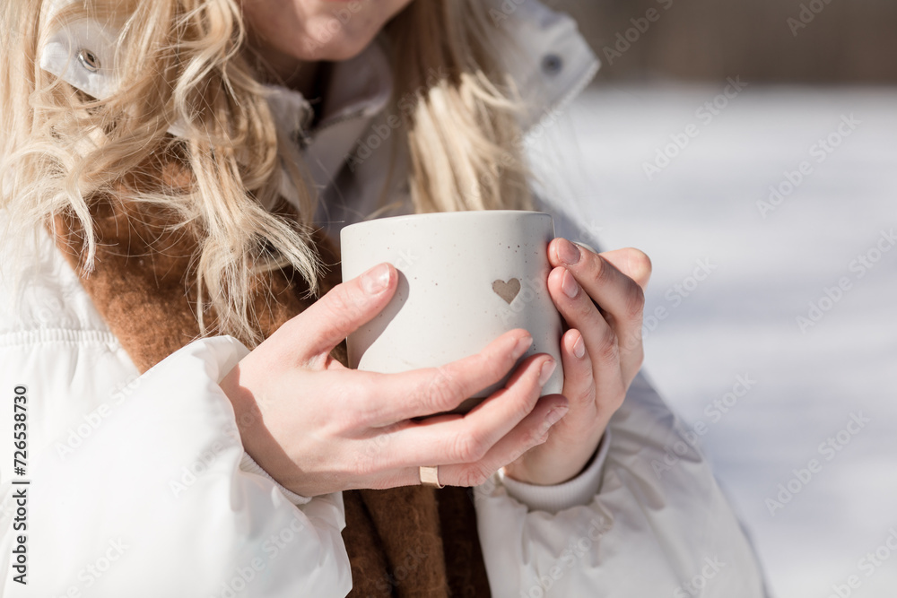 Woman drinking cup of hot tea or coffee outdoors in sunlight in cold winter day. Valentine day Woman drinking cup of hot tea or coffee outdoors in sunlight in cold winter day. Valentine day