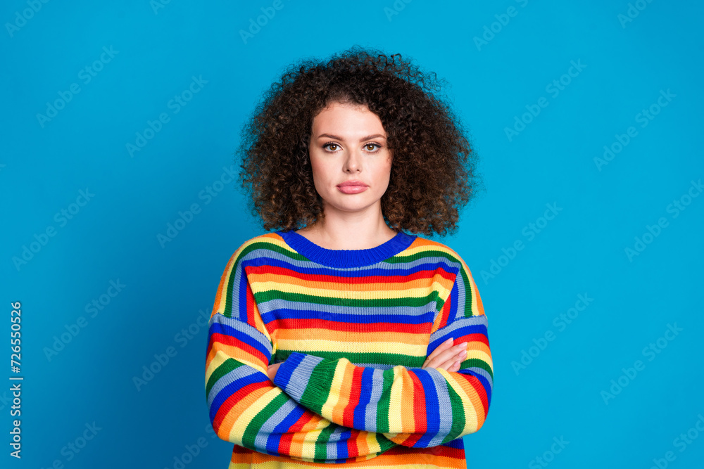 Photo portrait of pretty young girl crossed hands serious posing dressed stylish rainbow print outfit isolated on blue color background Photo portrait of pretty young girl crossed hands serious posing dressed stylish rainbow print outfit isolated on blue color background
