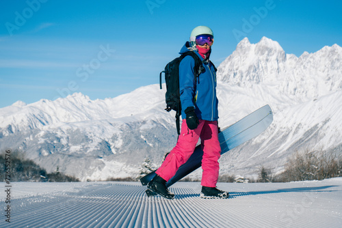 Female snowboarder walking on Snow trail from ratrak preparation, freshly groomed ski slope in high mountains ski resort