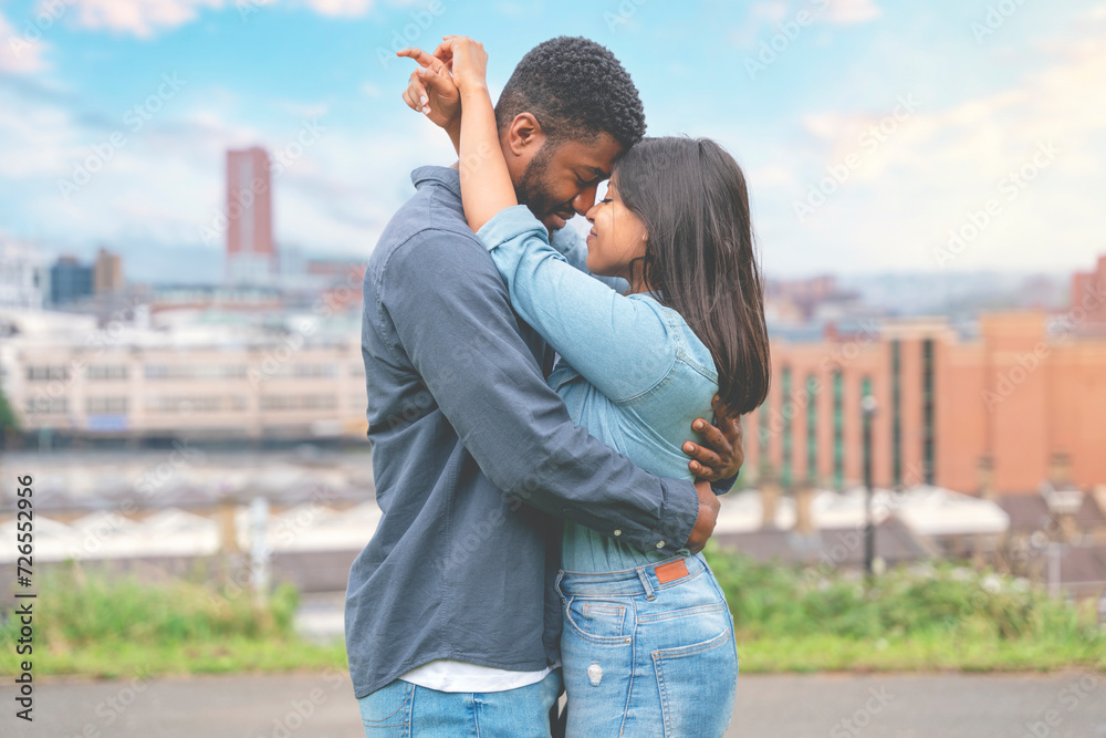 A handsome man and beautiful woman hugging each other in the park with a modern city in the background A handsome man and beautiful woman hugging each other in the park with a modern city in the background