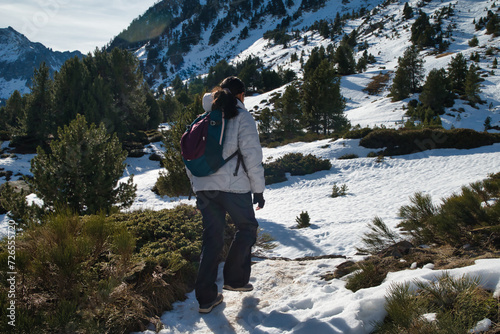 Hiking in the mountains of the Catalan Pyrenees. Girl traveler with backpack hiking in the mountains with snow. Lifestyle concept mountain sport.