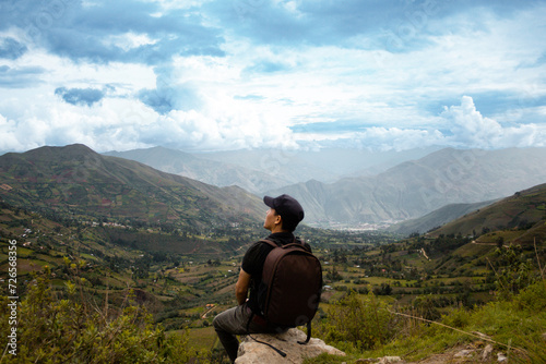 Una hombre turista con una mochila contemplando el asombroso paisaje de los Andes Peruanos con los brazos abiertos, concepto de turismo © Yoel Garay