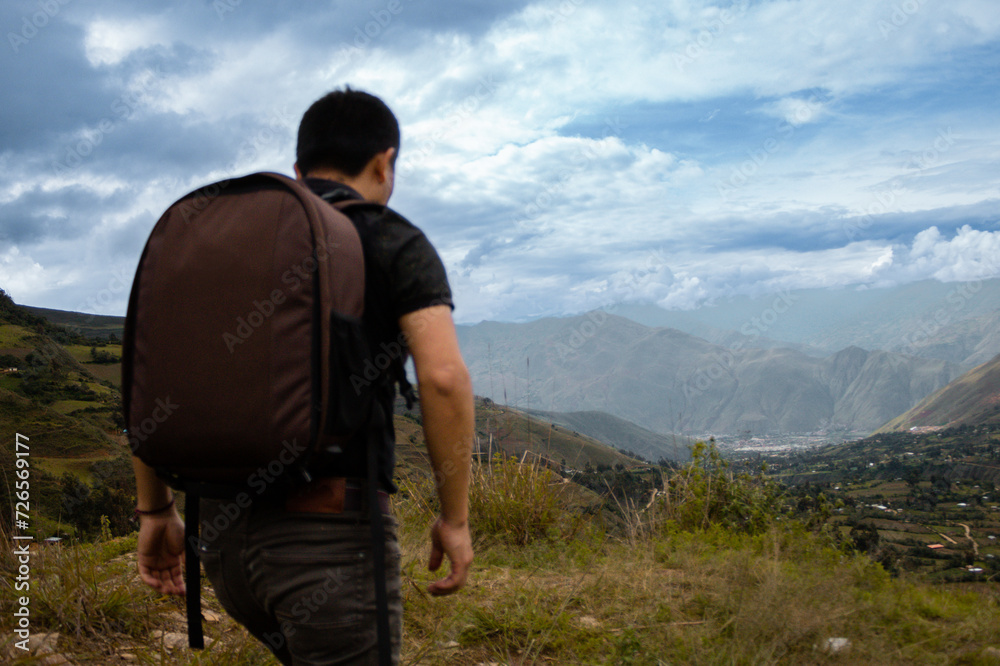 Naklejka premium Una hombre turista caminando con una mochila contemplando el asombroso paisaje de los Andes Peruanos con los brazos abiertos, concepto de turismo