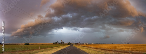 Dramatic storm clouds over a country road and flat farmland photo