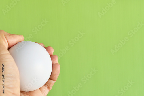 Mano sosteniendo una pelota anti estrés blanca, concepto de relajación y ejercicios para la mano. Espacio para texto al lado derecho. photo