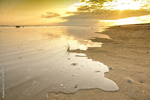 Ondergaande zon met reflectie van de wolken over de Oosterschelde in Nederland. Het zeewater stroomt tijdens het opkomende getijde over de schorren. photo