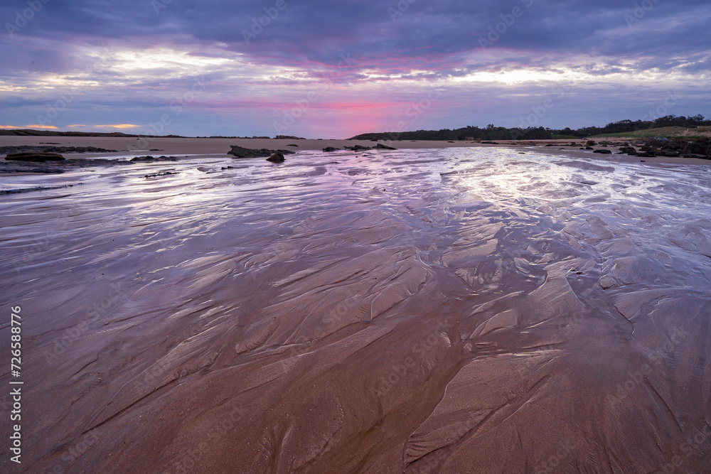 Low angled view of twilight colours reflecting off wet sand on a coastal beach Low angled view of twilight colours reflecting off wet sand on a coastal beach