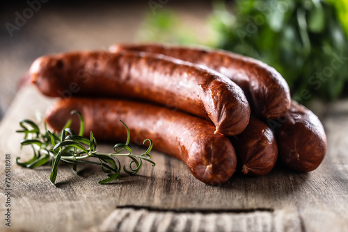 Pepper pork smoked sausages with rosemary on a cutting board