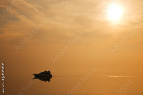 Recreatief varen met schip op de Oosterschelde in Zeeland, Nederland. De ondergaande zon geeft een oranje kleur over het water photo