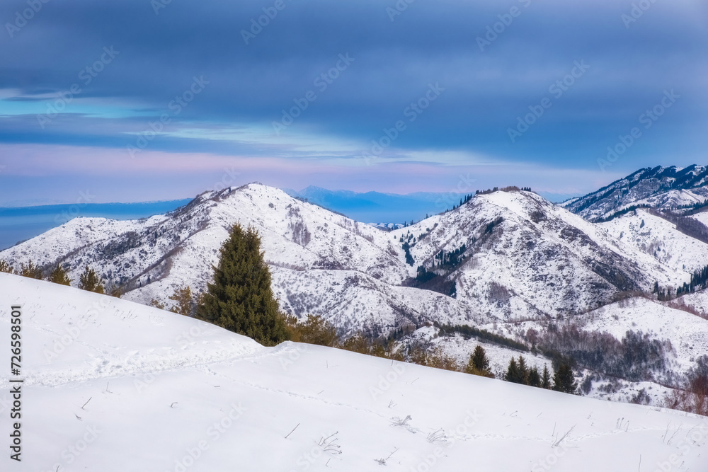 Winter mountain landscape at sunset. Hills and forest are covered with snow on the Kok Zhailao plateau in Almaty, Kazakhstan.