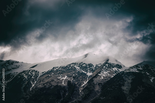 Beautiful mountain landscape. Clouds in the sky. Green grass. Snow on mountain peaks.