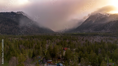 Beautiful mountain landscape. Clouds in the sky. Green grass. Snow on mountain peaks.