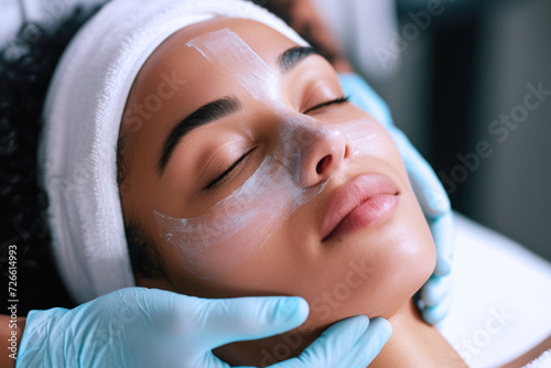 Beautician doing facial skin care for Afro girl in beauty salon