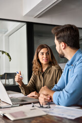 Two busy professional business people working in office with laptop computer. Middle aged female executive manager talking to male colleague having conversation sitting at workplace. Vertical