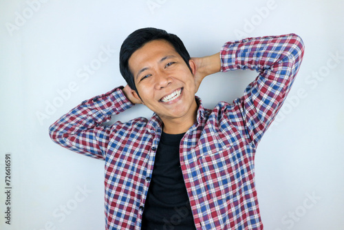 Smiling asian man with arm behind head relaxing peacefully in free time isolated on white background #726616591