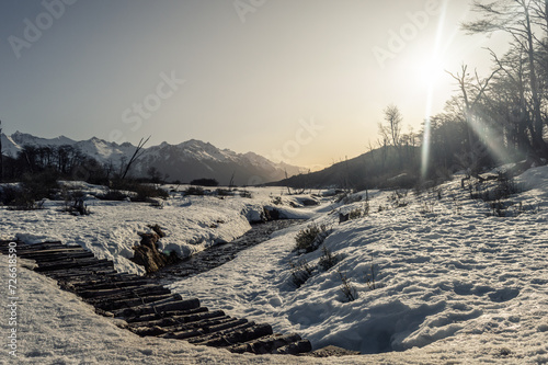 Snow covered bridge with Andes mountains in the background at golden hour. Ushuaia Emerald Lagoon