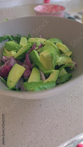 Close up of woman hands cutting avocado and putting them in bow, vertical video