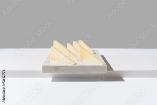 Trozos de queso de oveja curado. Queso manchego sobre un plato de mármol y fondo gris. Aperitivo español 
