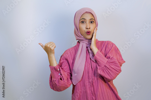 Cheerful muslim woman happy presenting and pointing. using hand to presenting something concept photo