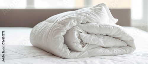 A white folded duvet lying on bed of bedroom hotel or home with sunlight background. AI generated photo
