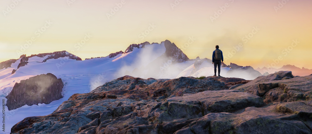 Adventurous Man Hiker on top of peak. Mountains in background. Adventure Composite 3d Rendering. Aerial Image of landscape from BC, Canada. Sunset