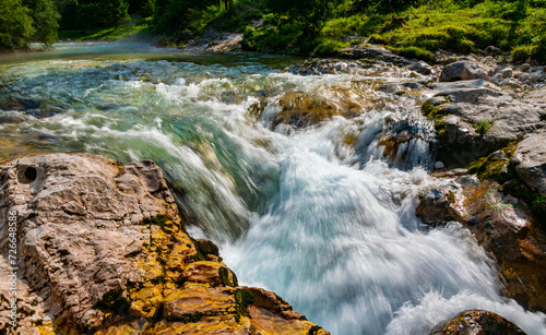 Cascade of famous Soča or Isonzo River (Emerald River) in Slovenia, near Bovec in the Julian Alps. Clear turquoies water splashing into limestone canyon on a sunny day. Idyllic nature and holiday spot #726648586