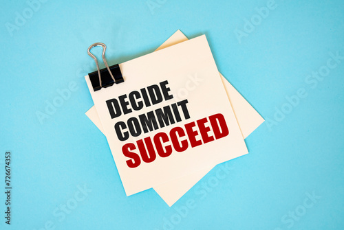 Text DECIDE COMMIT SUCCEED on sticky notes with copy space and paper clip isolated on red background. Finance and economics concept.