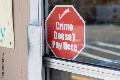 "Crime Doesn't Pay Here" warning signage at the entrance to a retail store. Organized retail crime (ORC) concept.