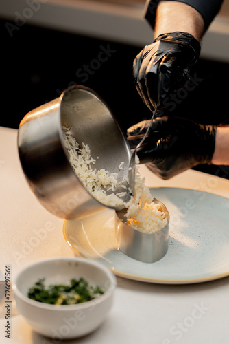 professional kitchen in a hotel restaurant close-up the cook puts cooked rice from a pot into a form