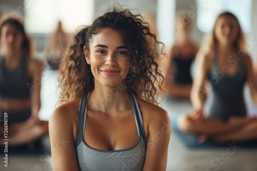 A woman is smiling in front of a group of women doing yoga photo