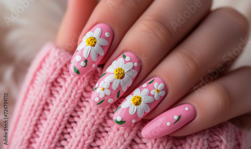 cute pink daisy nail design on manicured nails with cozy sweater background