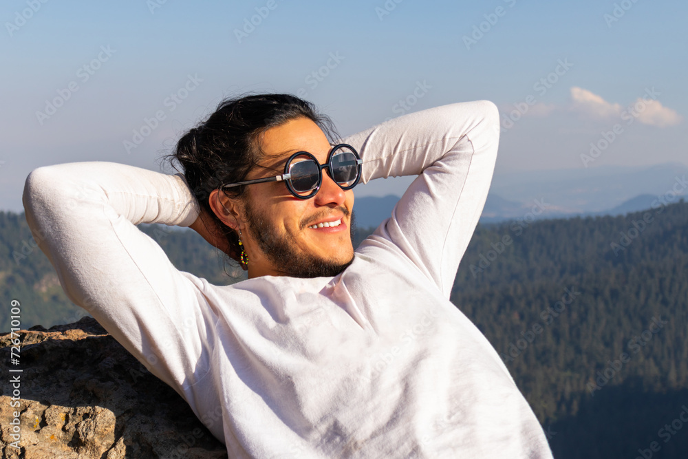 Cheerful young man resting on rocky mountain Cheerful young man resting on rocky mountain