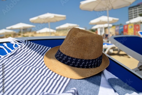 An elegant hat lies on a beach towel. Summer beach holiday. #726715921