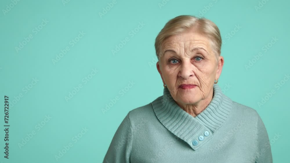 Angry granny of 60-70 years with appealing appearance in blue sweater looking with disgust, squinting eyes, pursing lips showing sign of supressed anger. High quality 4k footage Angry granny of 60-70 years with appealing appearance in blue sweater looking with disgust, squinting eyes, pursing lips showing sign of supressed anger. High quality 4k footage