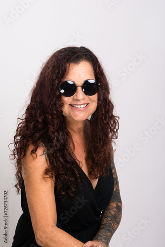 Beautiful curly-haired woman wearing sunglasses and black clothing smiling. © Thales